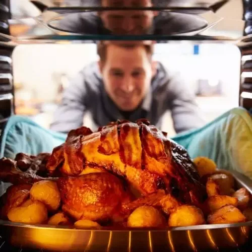 Man pulling turkey out of the oven
