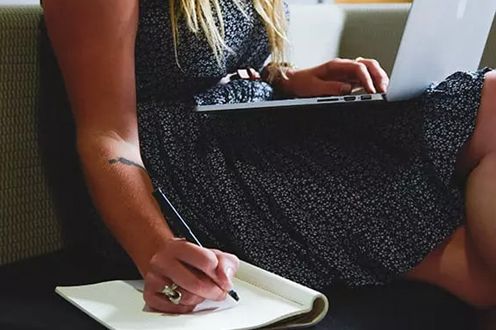 <p>Photo of a woman writing in a notebook</p>
