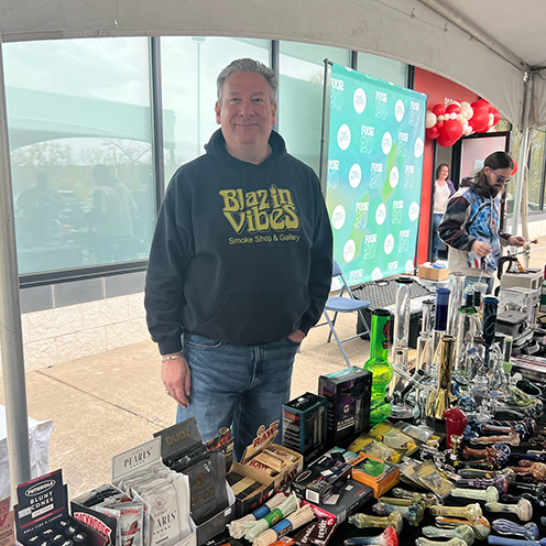 <p>Shop owner standing behind table with their products displayed</p>
