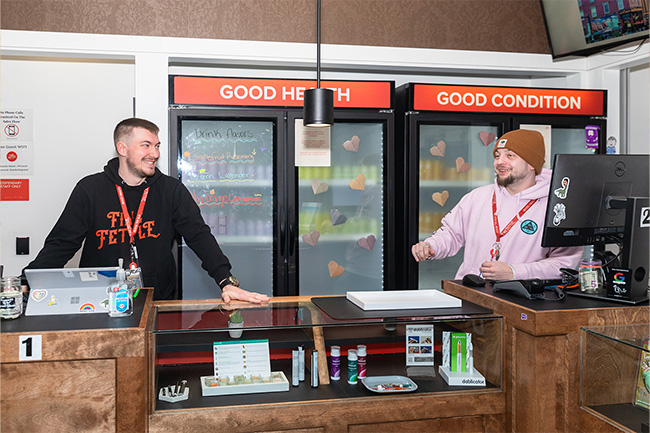 Two employees interacting behind the counter at Fine Fettle's Willimantic store