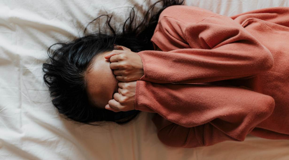 Person laying down with hands over their face