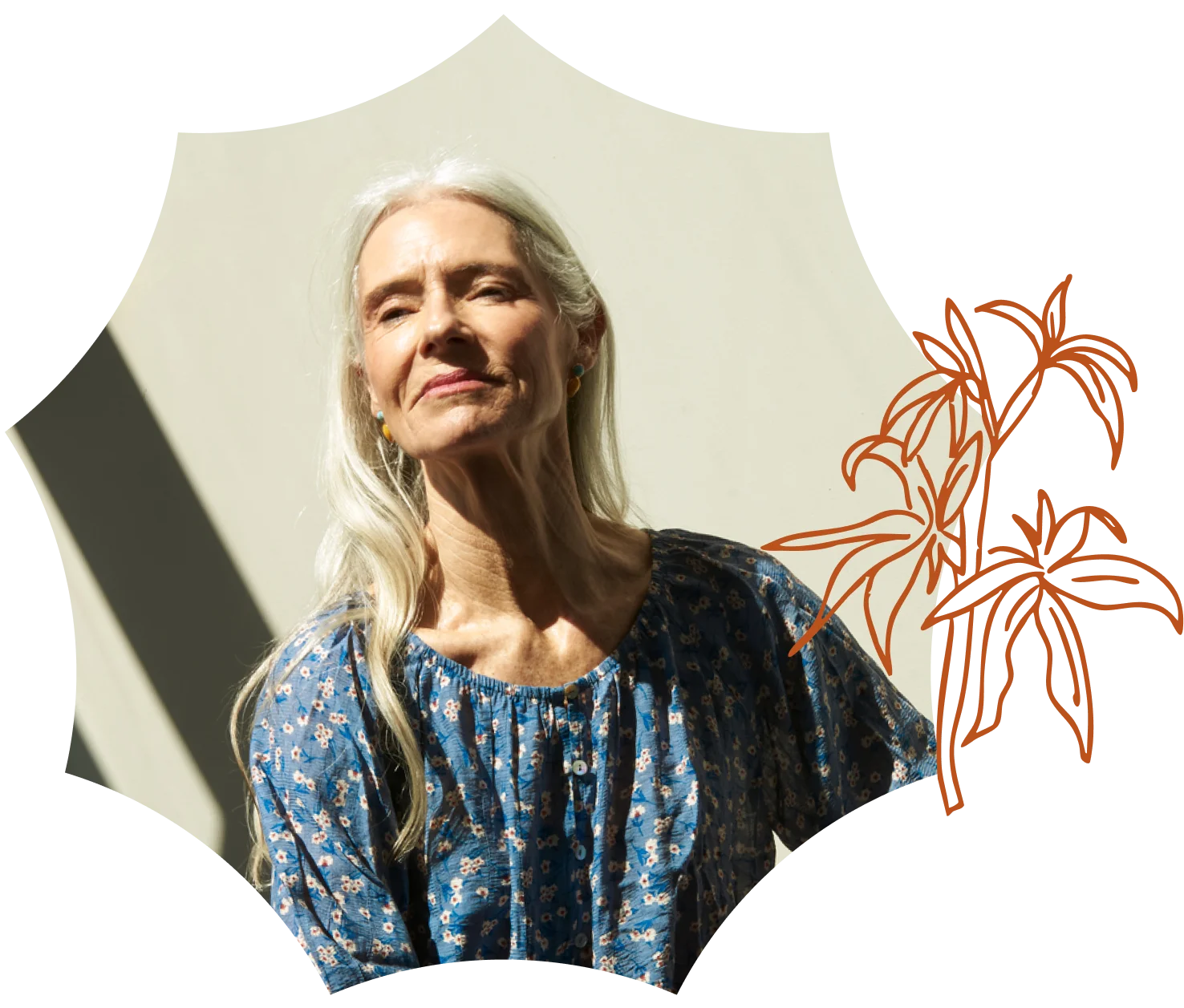 Older woman with long gray hair, in a blue floral blouse, stands in sunlight with a soft smile; brown abstract botanical art hints at a nearby cannabis dispensary on the right.