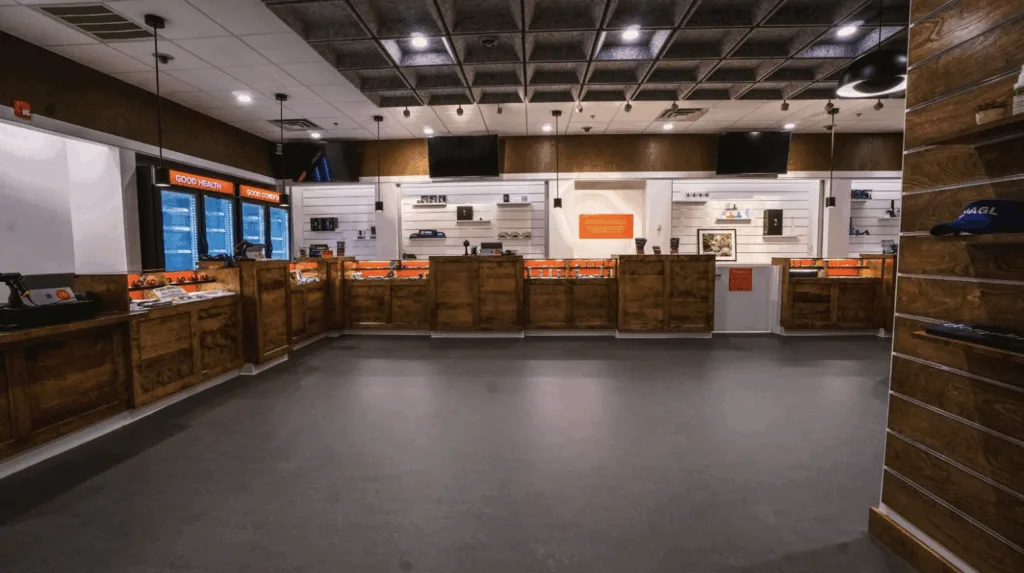 A modern indoor retail counter with wood paneling, glass display cases, and shelves holding various products against the back wall under bright lighting.