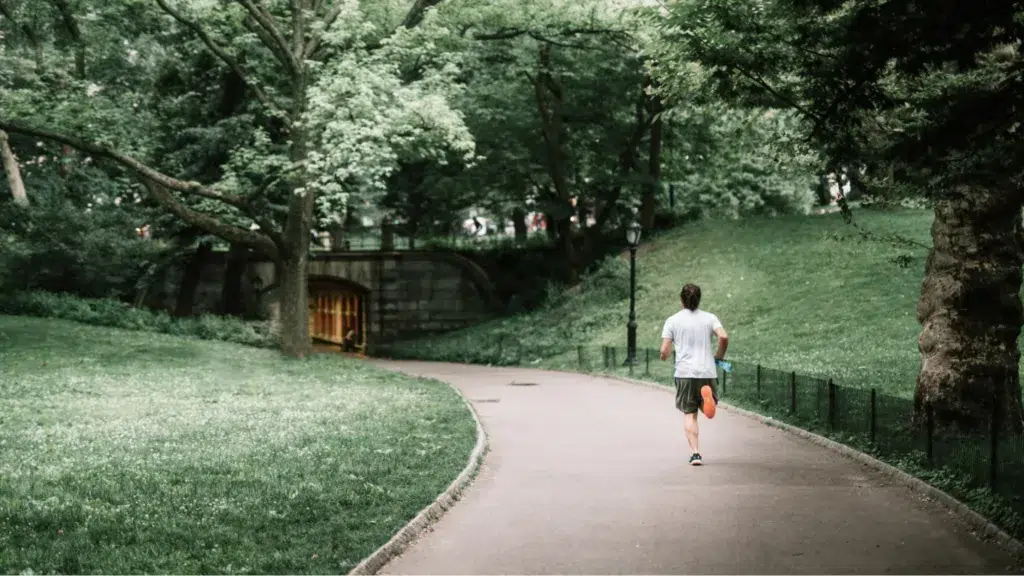 Man jogging outdoors in green park while on a cannabis t-break