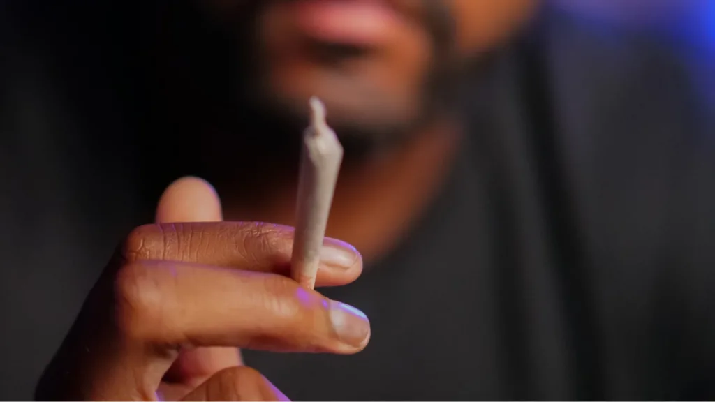 Man holding a cannabis pre-roll, considering a tolerance break