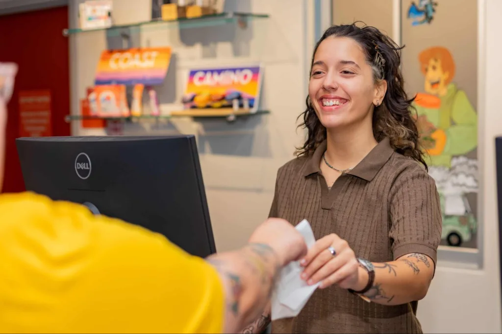 smiling budtender handing a bag to a customer at checkout