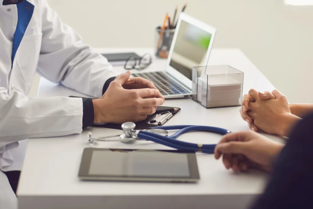 Doctor and patient sit around a table with a stethoscope and laptop 