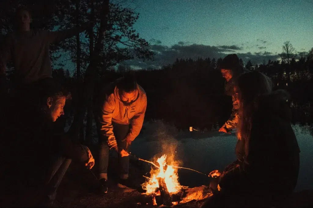 A group of friends sitting in front of a bonfire after sunset. Source - Pexels